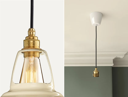 Close up of an E27 Signature Brass suspension set on a Paper Cream lampshade on the left. On the right, an E27 Brass pendant set is hanging from the ceiling