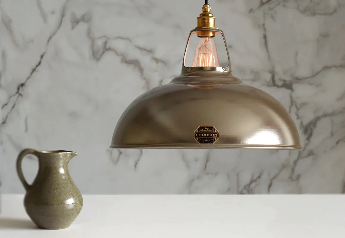 A large Antinium shade hanging over a table above a grey water jug and a golden spoon and fork. The background is a marble wallpaper