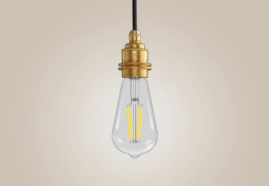 E27 LED Lightbulb hanging over a light background. The lightbulb is fitted with a Coolicon Brass Suspension Set