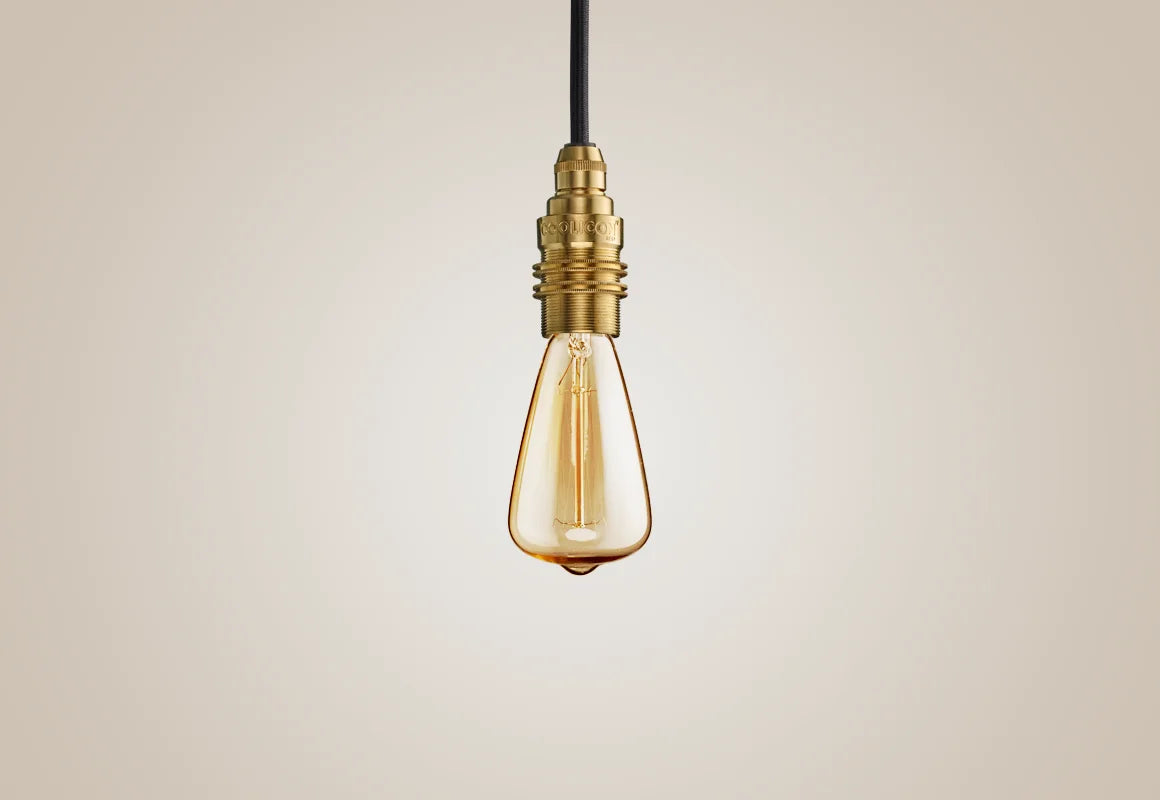E14 decorative Lightbulb hanging over a light background. The lightbulb is fitted with a Coolicon Brass Suspension Set