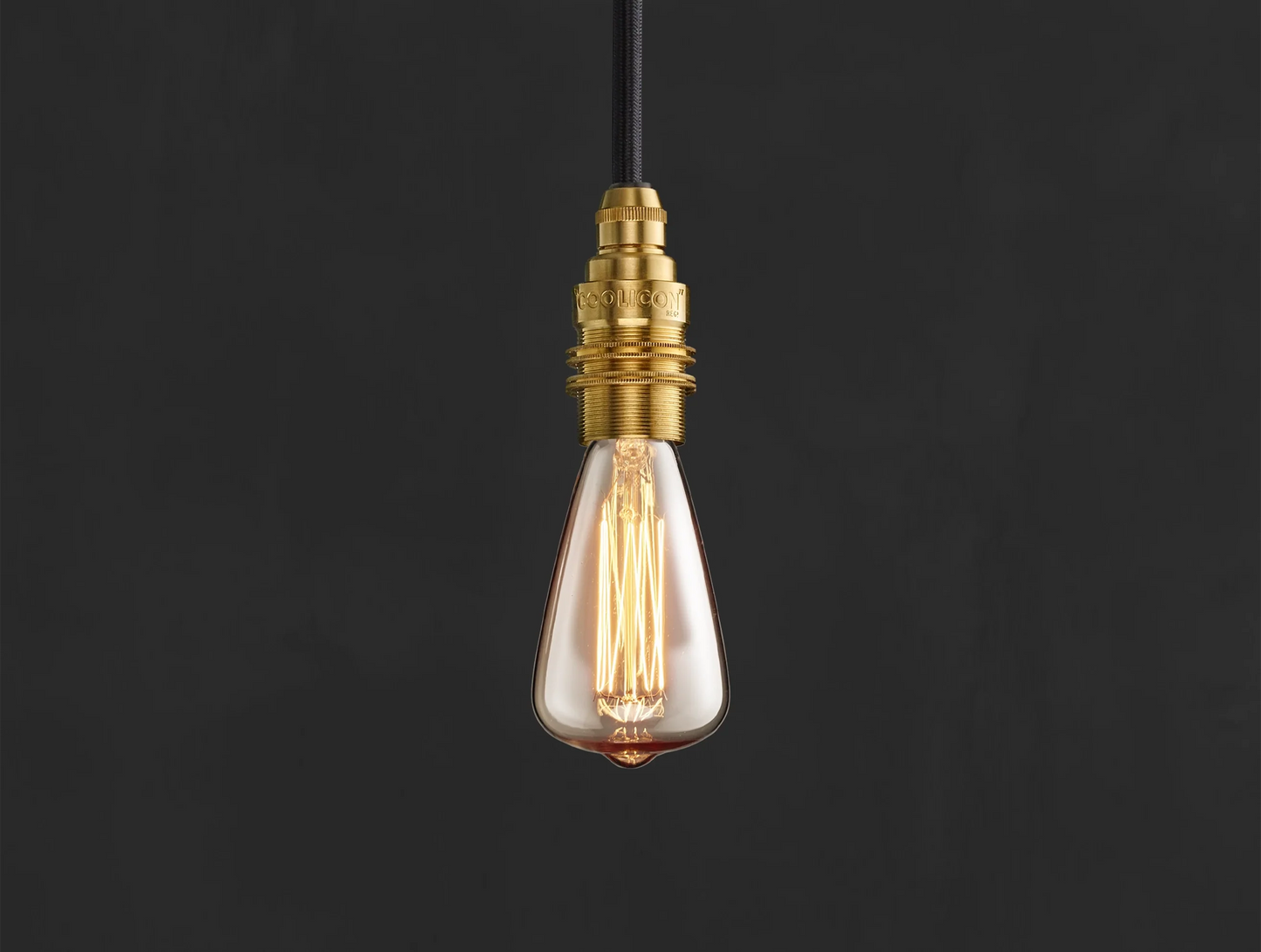 E14 decorative Lightbulb hanging over a black background. The lightbulb is fitted with a Coolicon Brass Suspension Set