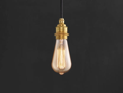 E27 decorative Lightbulb hanging over a black background. The lightbulb is fitted with a Coolicon Brass Suspension Set